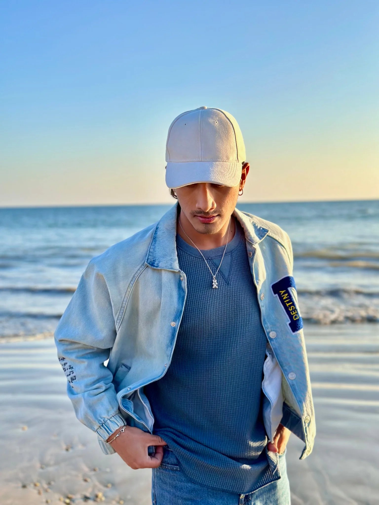 Model wearing white suede cap and rebel bear pendant